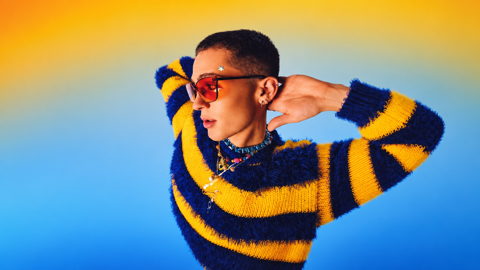 Man wearing red sunglasses and a blue and yellow striped sweater