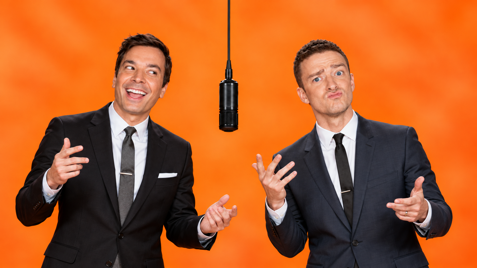 Two men in matching dark suits illustrating a consistent cast and orange studio for a hotel lobby video